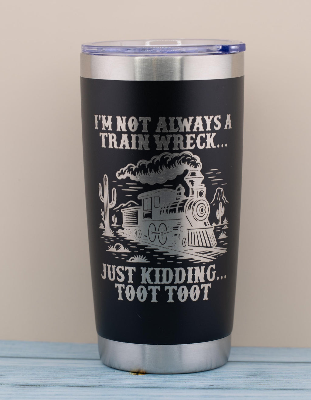 A black tumbler with a printed design on it, featuring a train and text that reads "I'm not always a train wreck... just kicking toot toot".