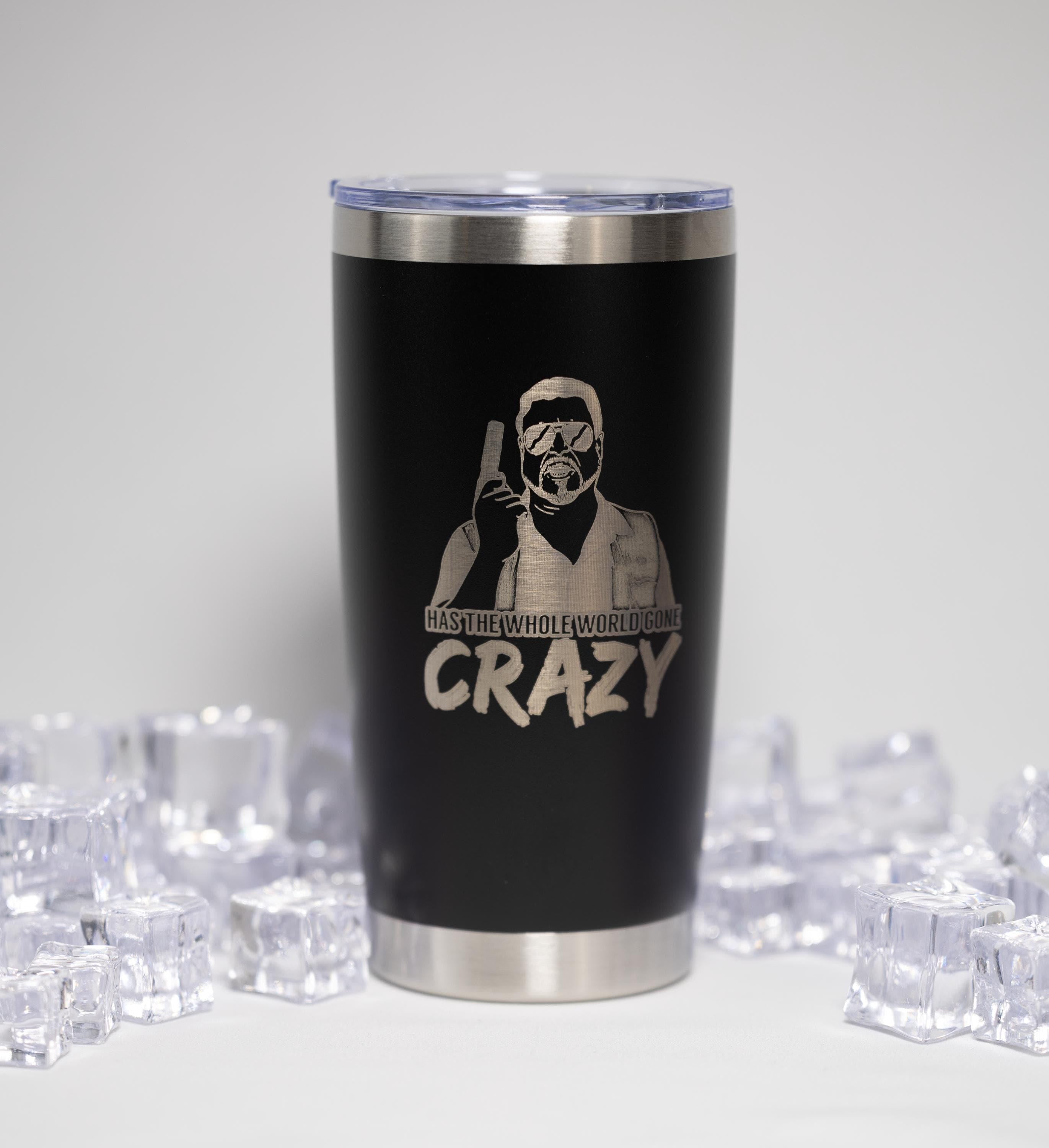 A black tumbler with a silver lid, featuring a printed design of a person wearing sunglasses and holding a gun, along with the text "Crazy" and "HASHTERS WHO GOES CRAZY" printed on it.