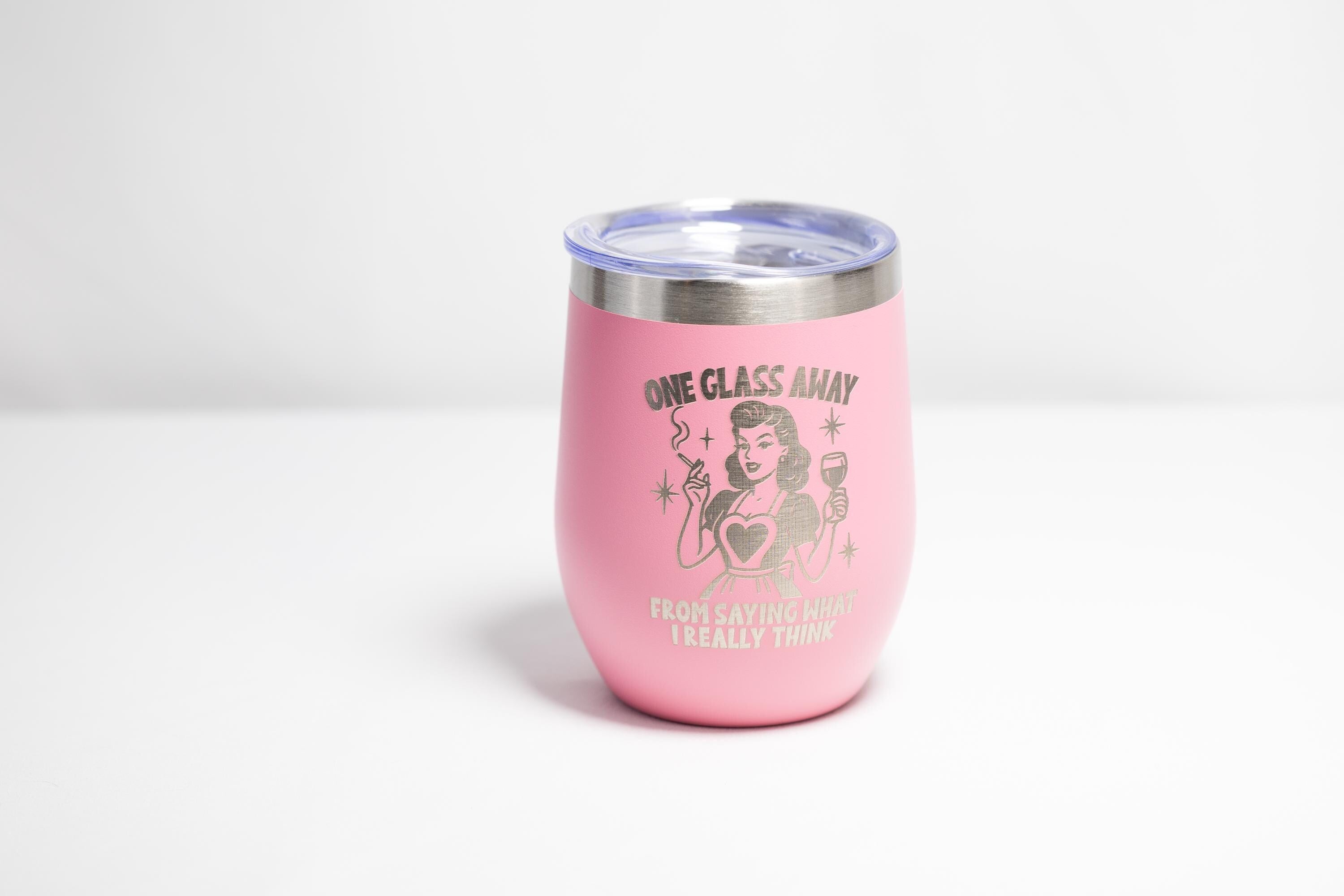 A pink thermos with a printed design on it, featuring a woman holding a wine glass and the text "ONE CLASS AWAY" along with the phrase "FROM SAYING WHAT I REALLY THINK".
