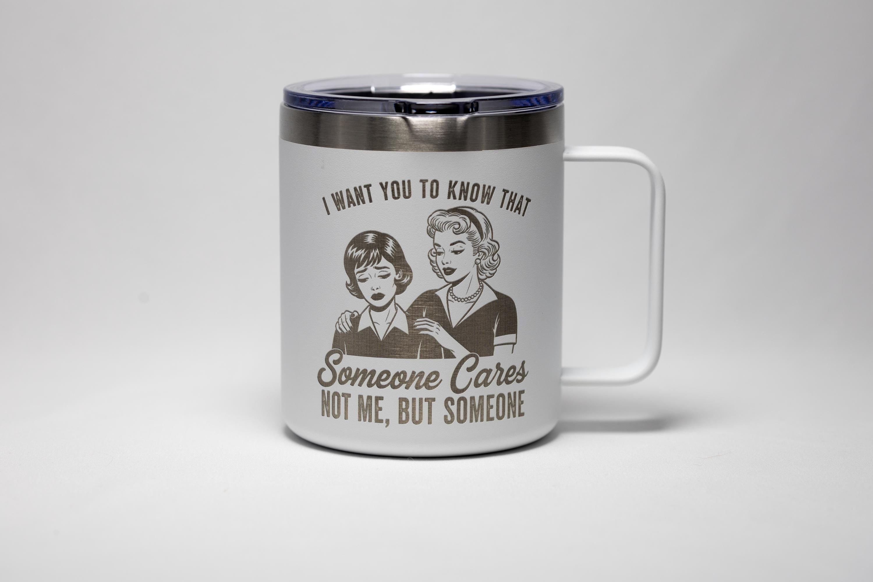 May include: White travel mug with a silver rim and handle. The mug features a retro illustration of two women with the text "I WANT YOU TO KNOW THAT Someone Cares NOT ME, BUT SOMEONE."