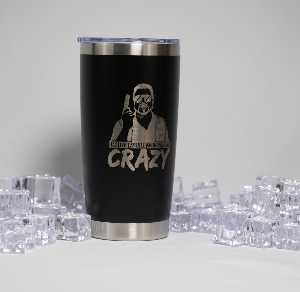 A black insulated tumbler with a silver lid, featuring a printed design of a person wearing a mask and holding a gun.