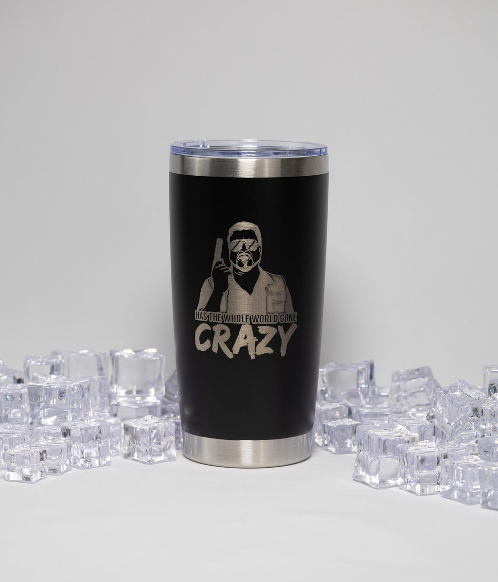 A black tumbler with a silver lid, featuring a printed design of a person wearing a mask and holding a gun, surrounded by numerous ice cubes.