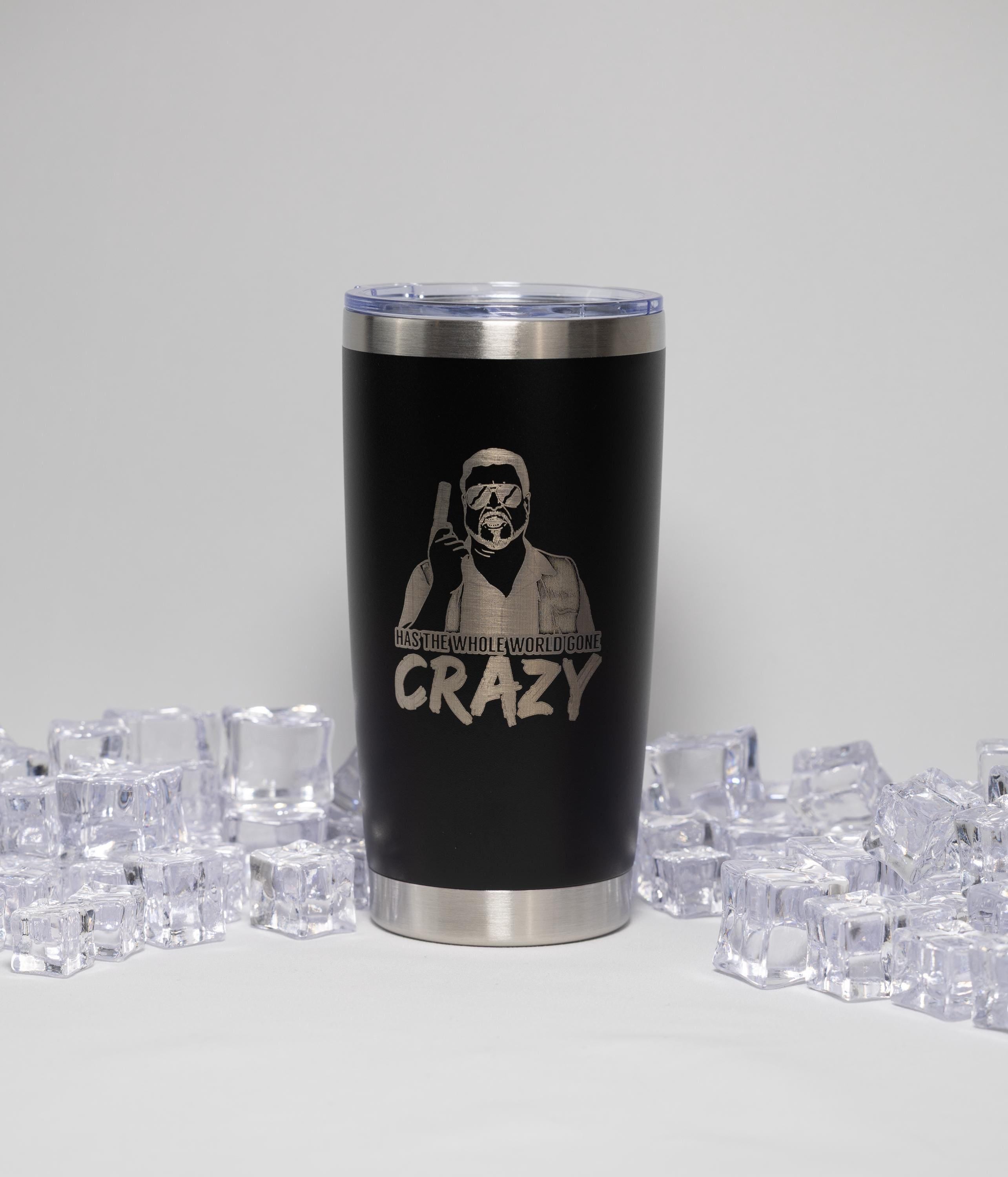 A black tumbler with a silver lid, featuring a printed design of a person wearing a mask and holding a gun, surrounded by numerous ice cubes.