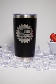 A black tumbler with a silver lid, featuring a logo that says "YouTube Certified Mechanic" on it, placed on a surface with ice cubes.