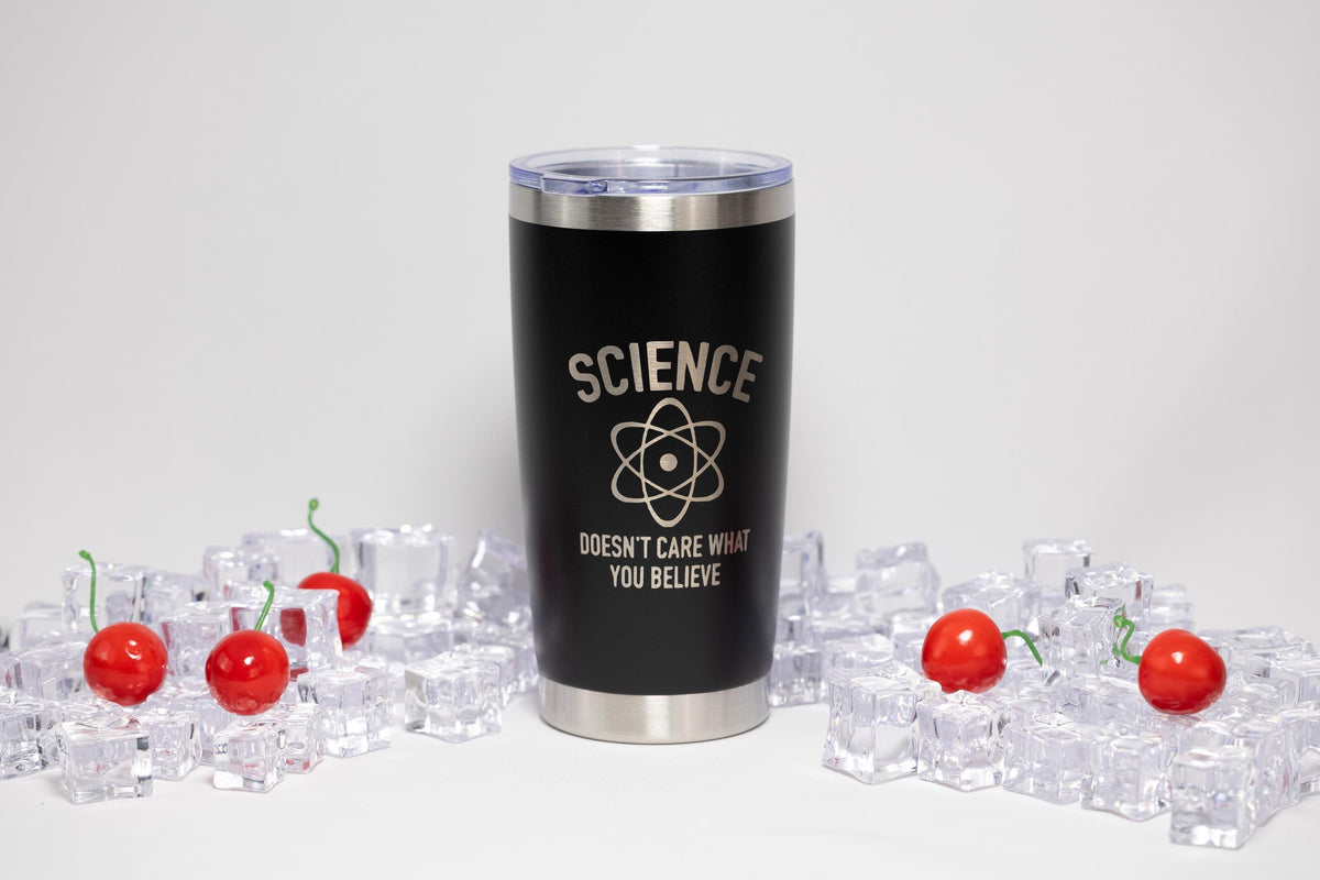 A black insulated tumbler with a silver lid, featuring the text "SCIENCE DOESN'T CARE WHAT YOU BELIEVE" on its side, is surrounded by ice cubes and cherry tomatoes.