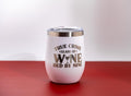 May include: White insulated wine tumbler with a silver rim and a clear lid. The tumbler features the text "TRUE CRIME GLASS OF WINE BED BY NINE" in silver lettering. The tumbler is on a red surface.
