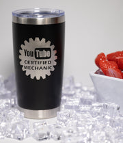 A black tumbler with a silver lid, featuring a logo that says "YouTube Certified Mechanic" on it, placed on a bed of ice cubes.