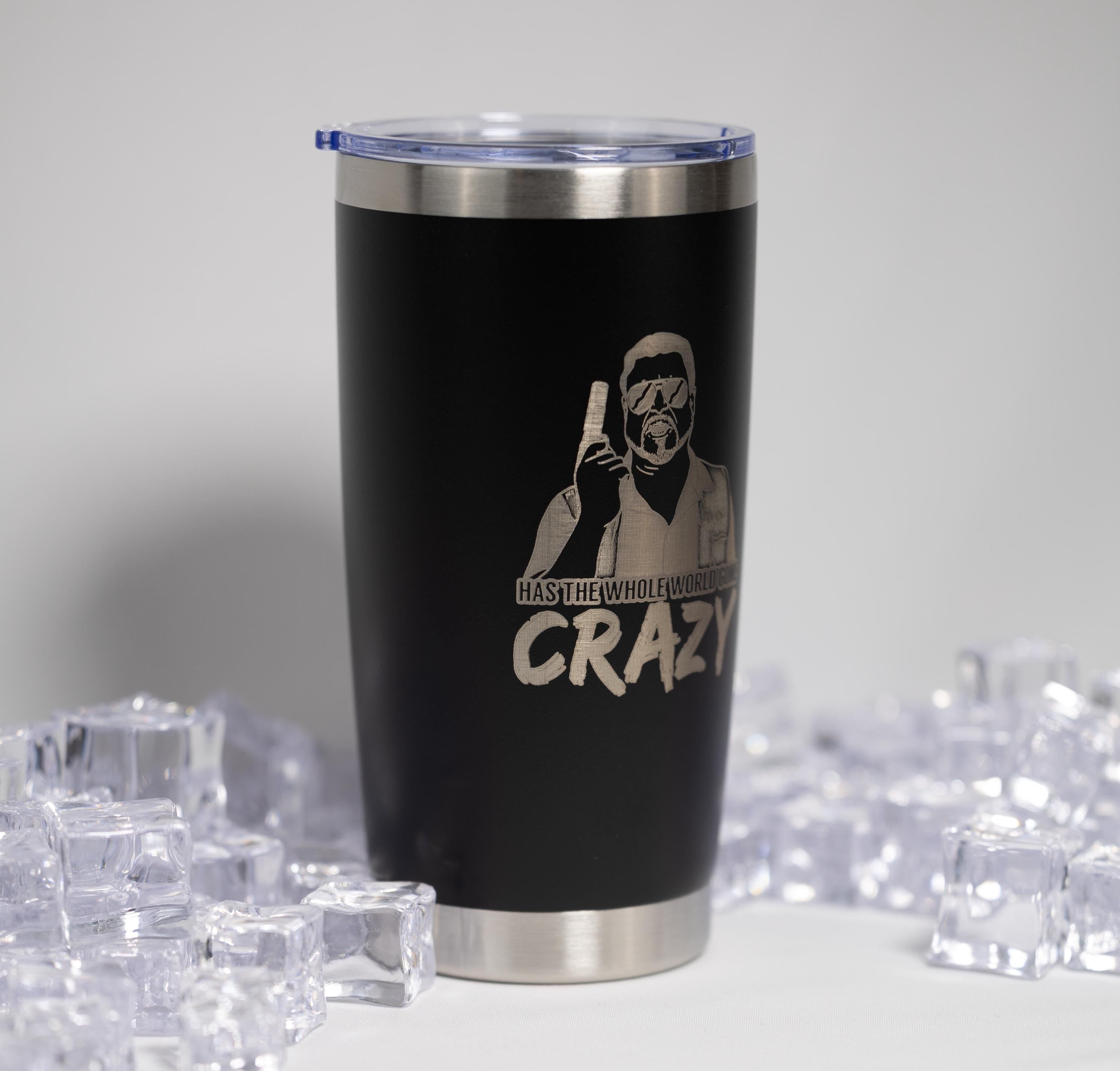 A black tumbler with a printed design and text on it, surrounded by ice cubes.