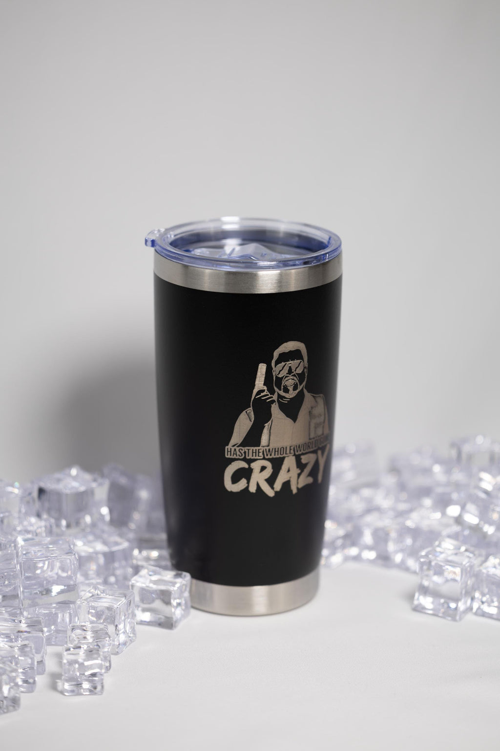 A black tumbler with a lid and a printed design on it, surrounded by ice cubes.