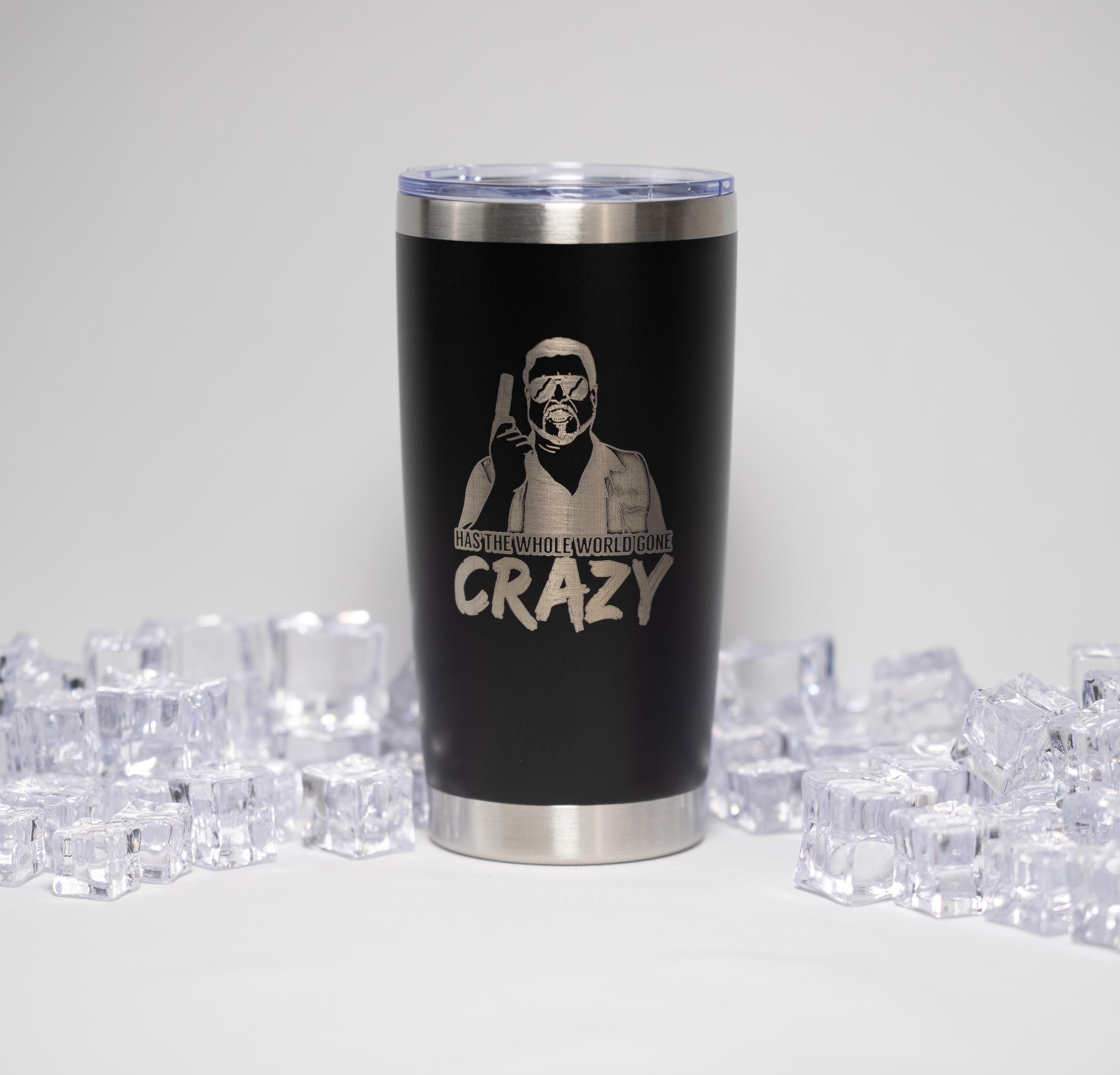 A black tumbler with a printed design and text on it, surrounded by ice cubes.
