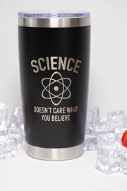A black insulated tumbler with a silver lid, featuring a white text logo that says "SCIENCE DOESN'T CARE WHAT YOU BELIEVE".
