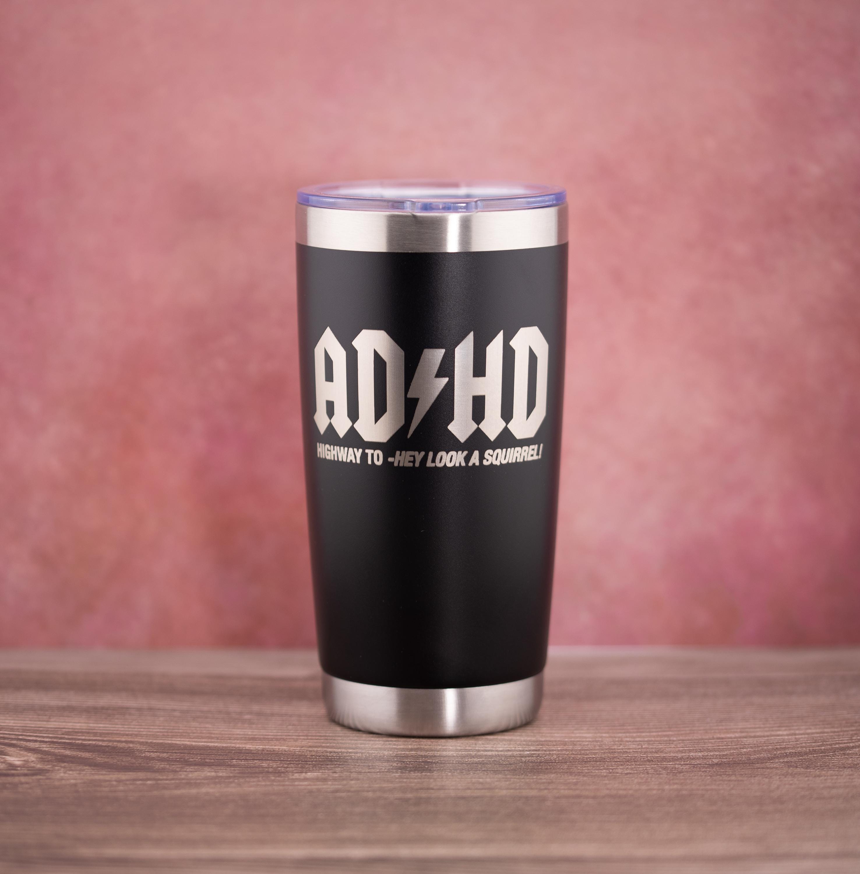 May include: A black stainless steel tumbler with a silver rim and lid. The tumbler features the white text "ADHD" with a lightning bolt and the phrase "HIGHWAY TO -HEY LOOK A SQUIRREL!" in a bold font.